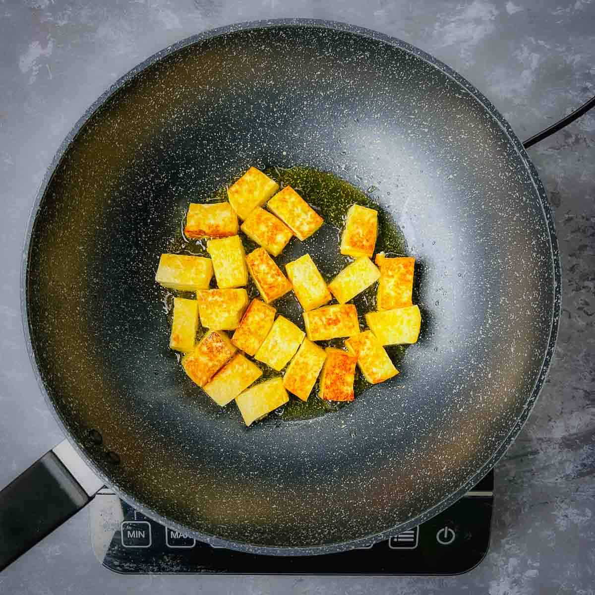 Fried paneer cubes in frying pan.