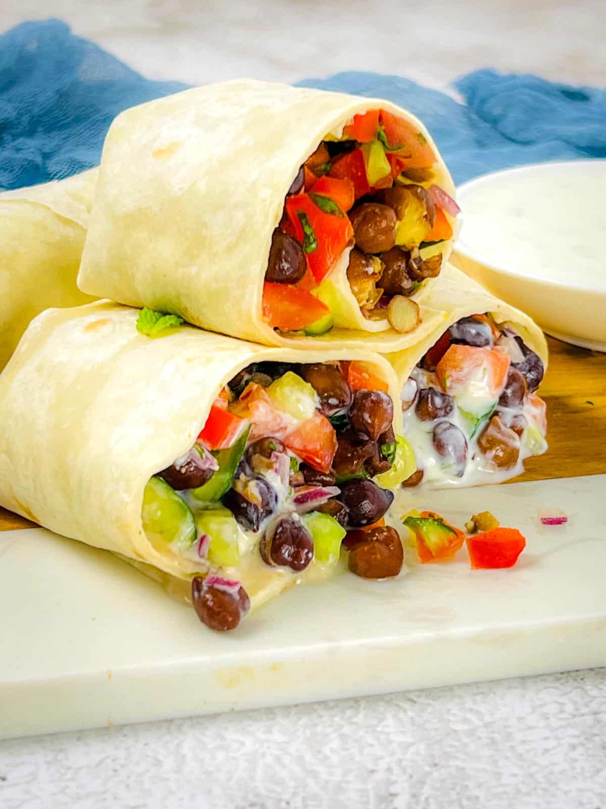 Black chickpea wraps cut and placed on wooden board.
