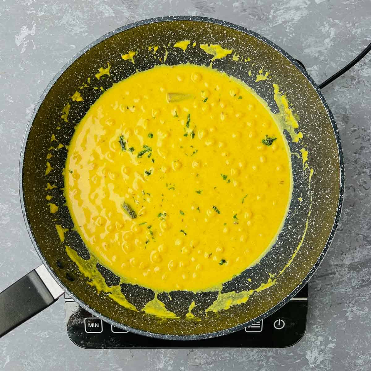 Chana madra simmered and garnished with cilantro in the frying pan.