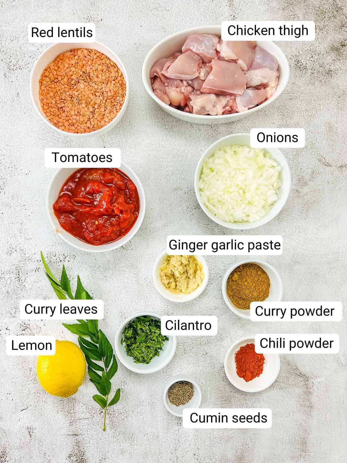 Ingredient to make chicken lentil curry placed on a white surface.
