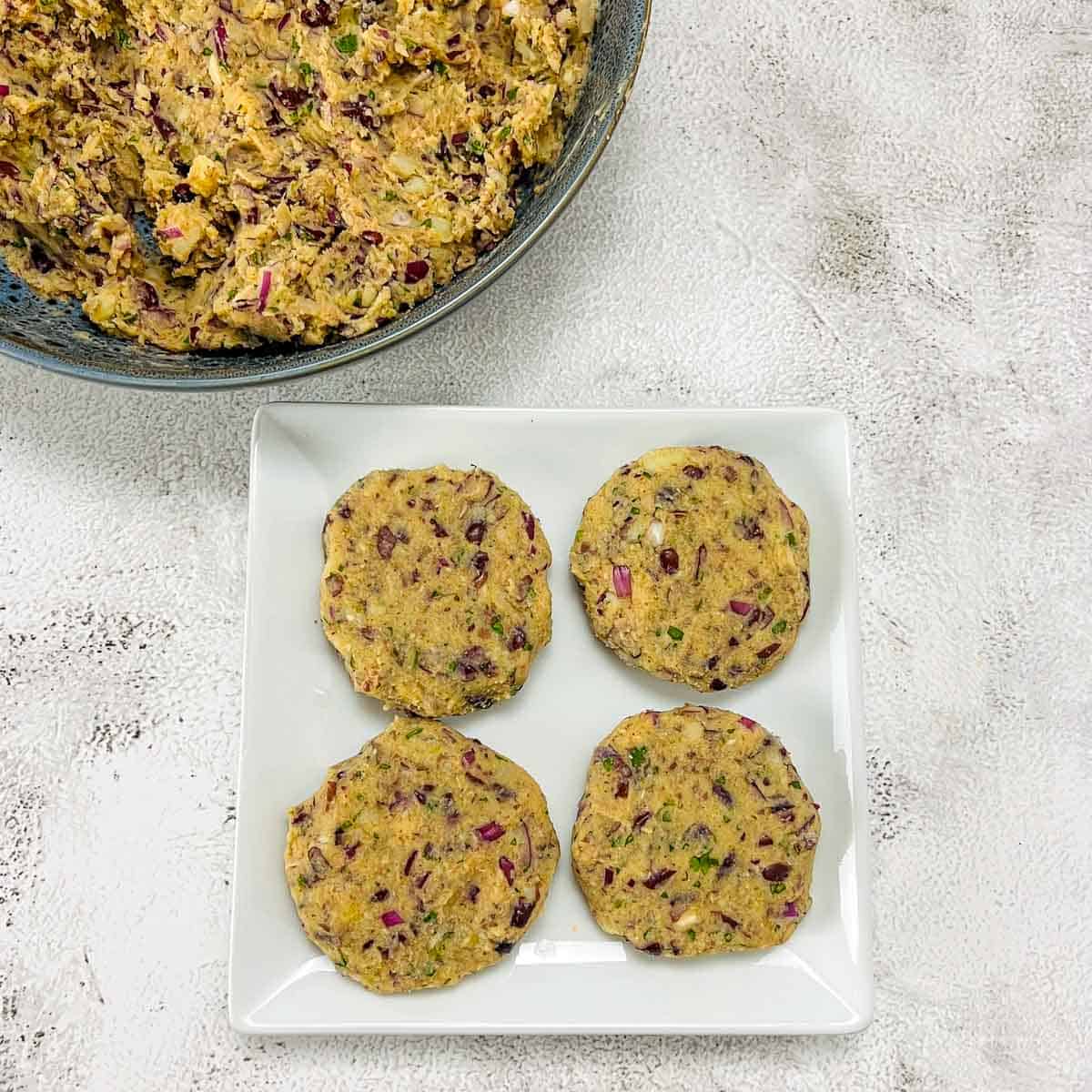 Shaped patties on a white plate with mixing bowl in the background.