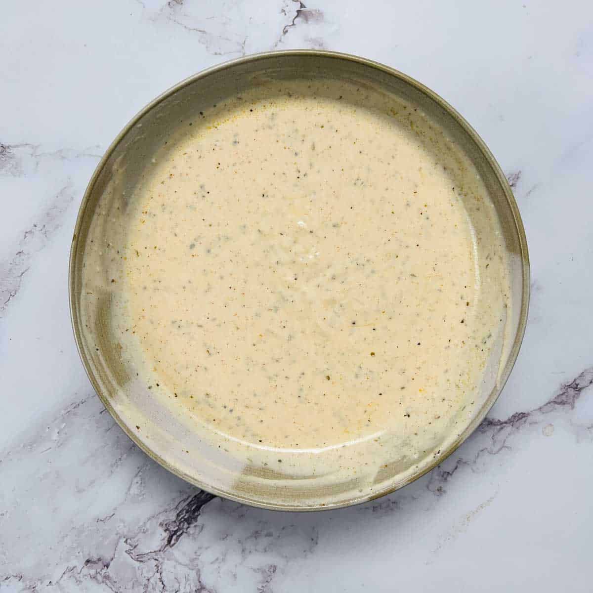 Garlic and yogurt sauce in a brown bowl.