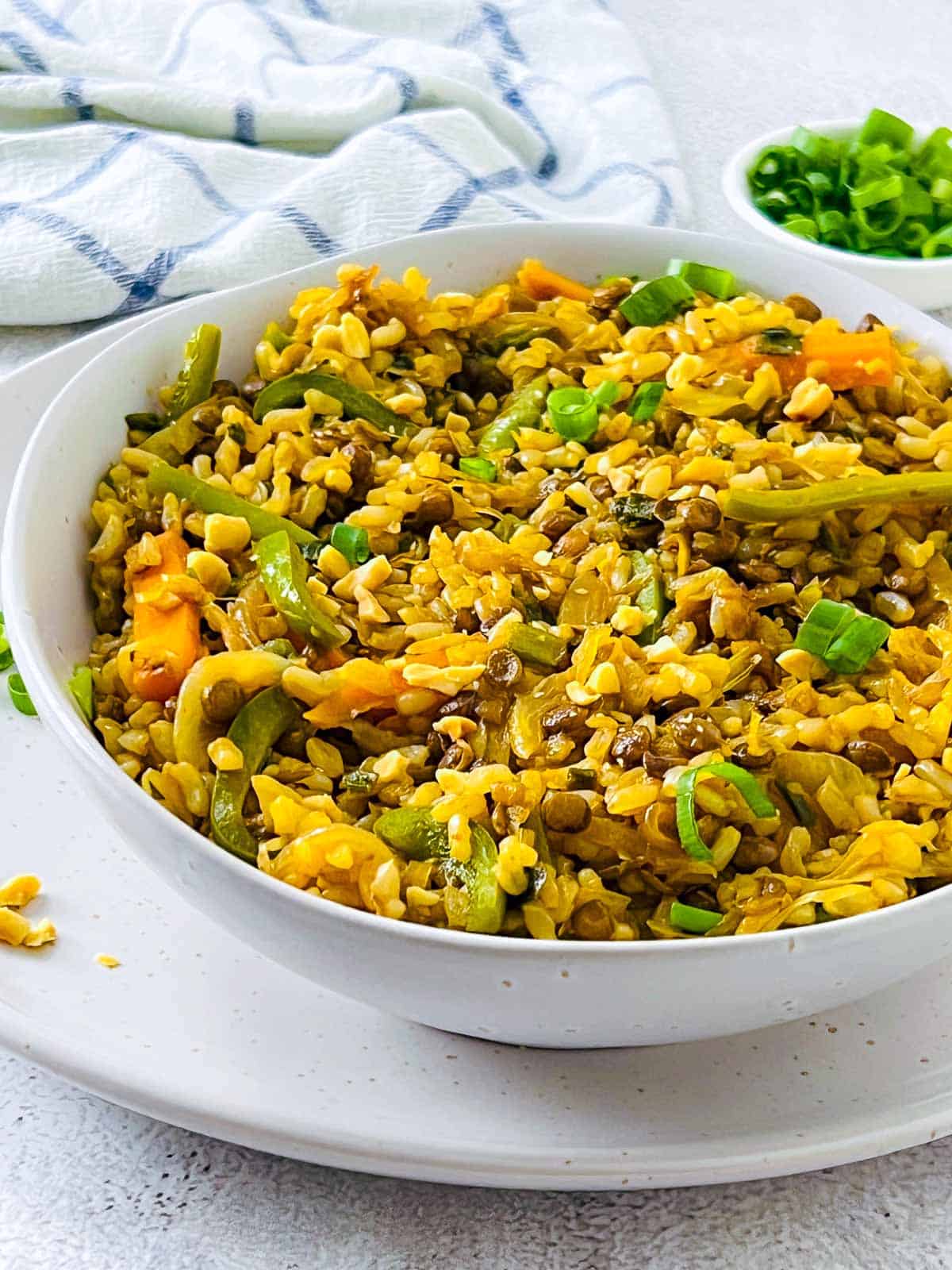 Brown rice and lentil stir fry garnished with crushed roasted peanuts.