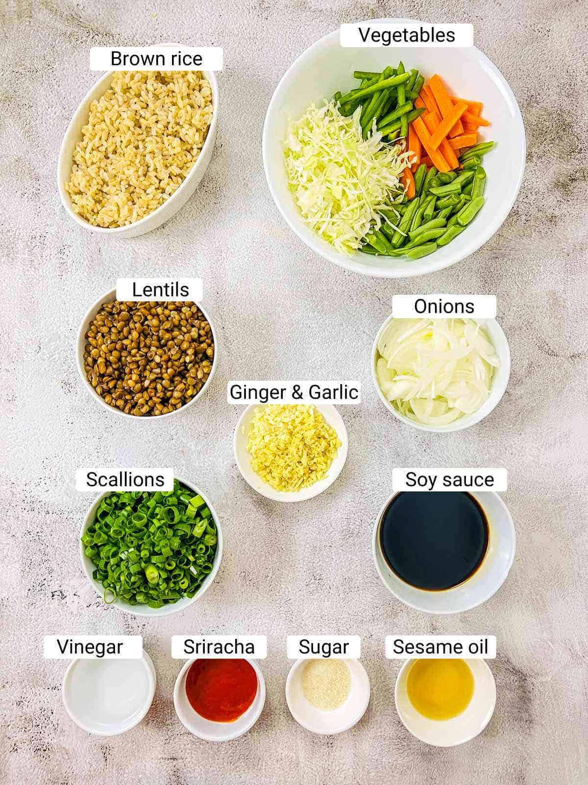 Ingredients to make brown rice lentil stir fry on a white surface.
