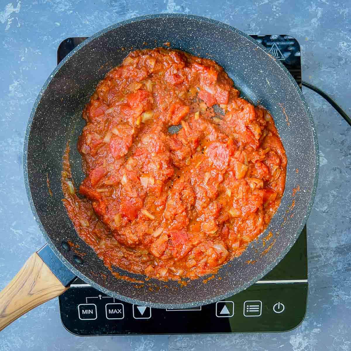 Sauteed onion, tomatoes, and spices in a skillet.