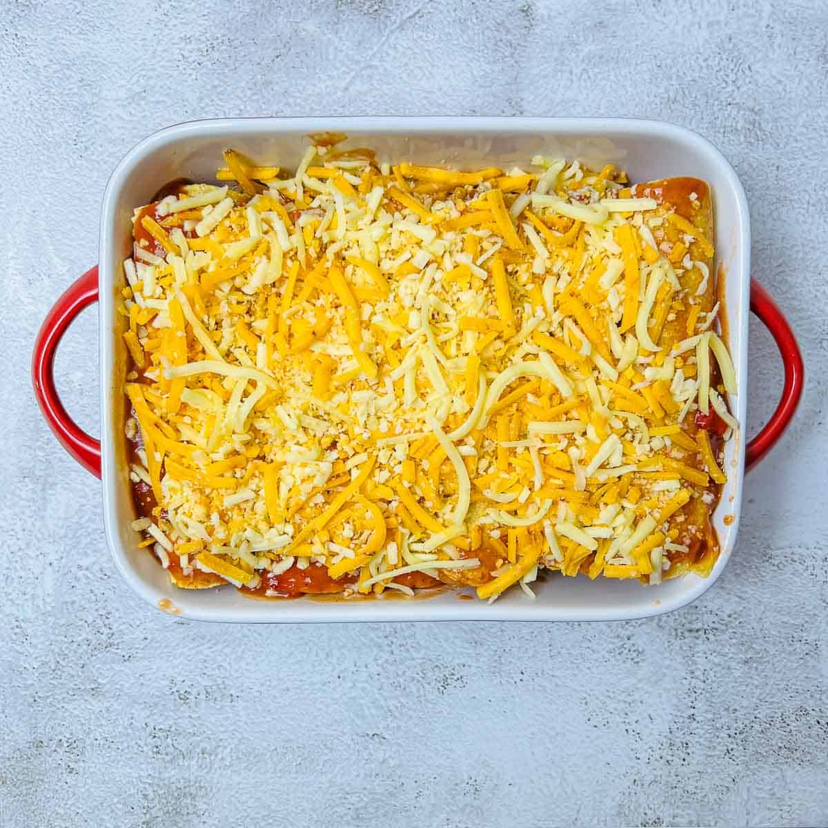 Filled tortillas topped with enchiladas sauce and cheese.