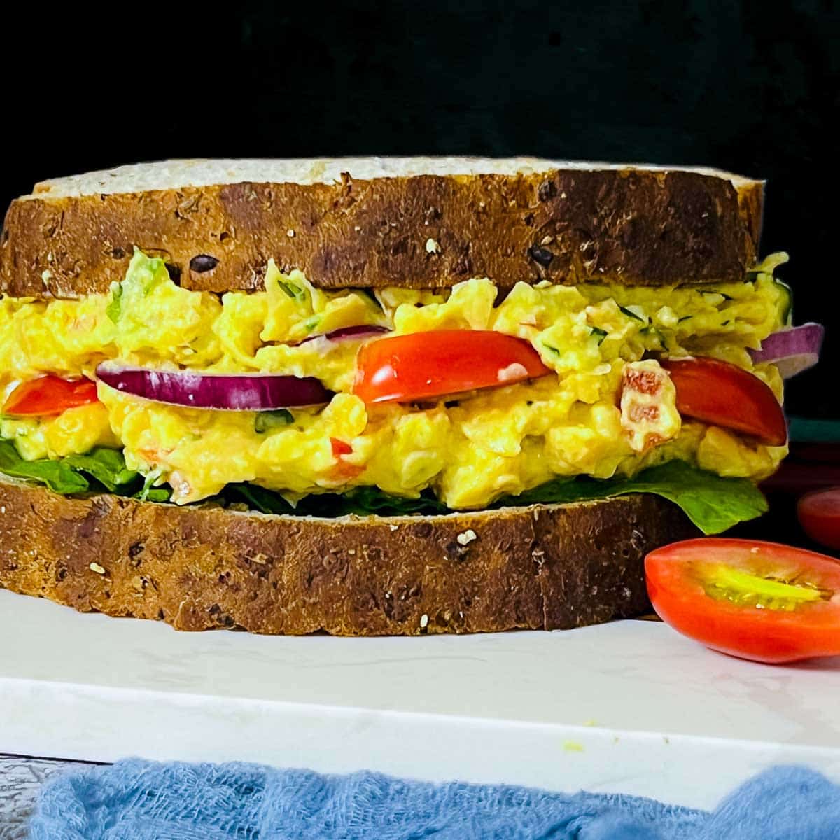 Chickpea salad sandwich on a white board.