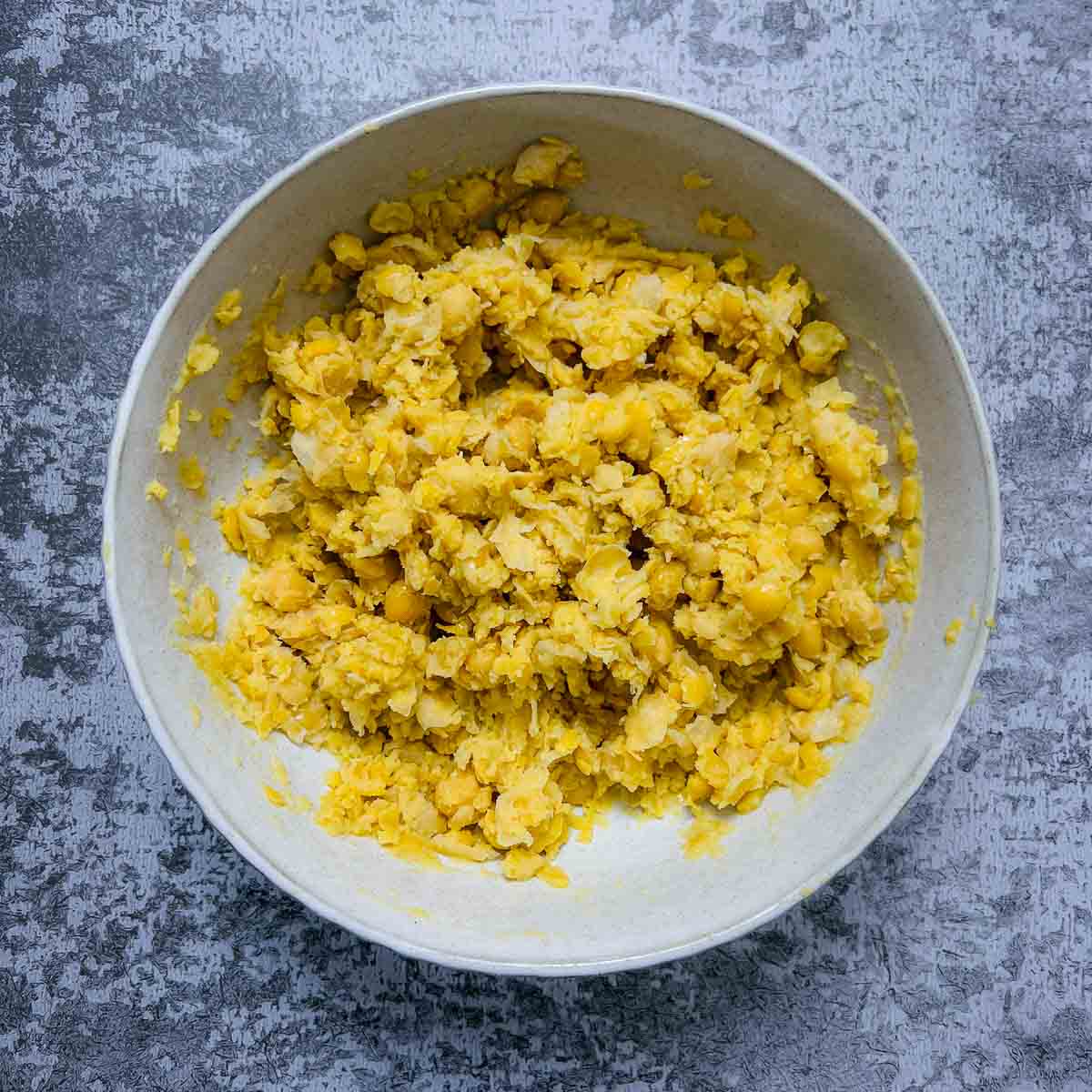 Mashed chickpeas in a white bowl.