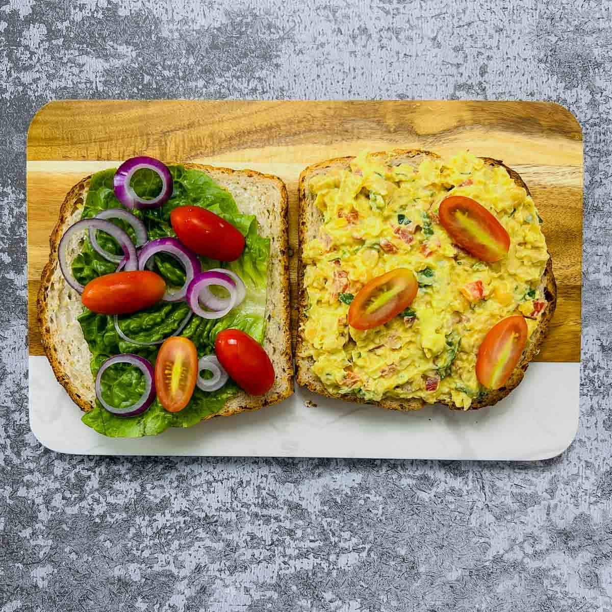Assembling chickpea salad sandwich.