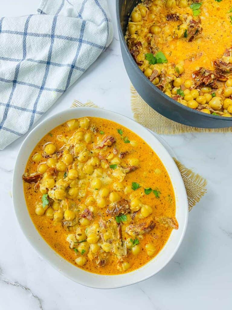 Marry me chickpeas in a white bowl with Dutch oven in the background.