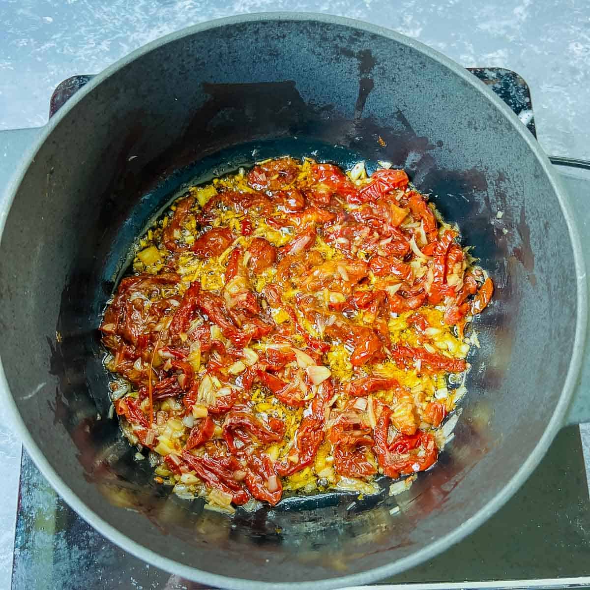 Sauted onion and sundried tomatoes in Dutch oven.