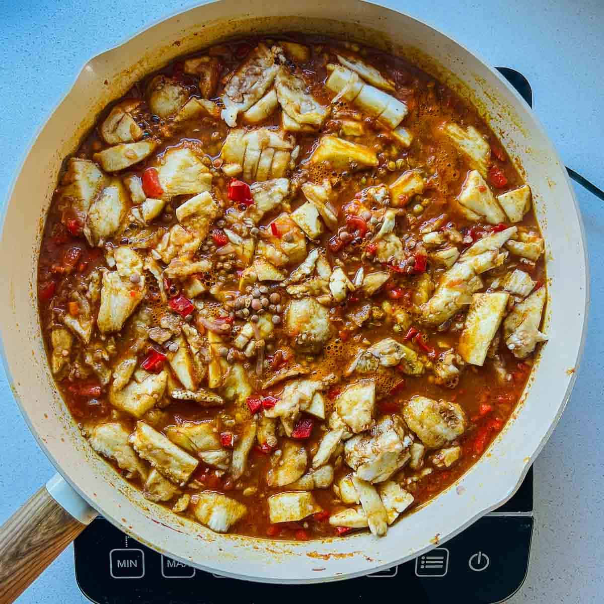 Lentils, scooped eggplant flesh, and spices in a frying pan.