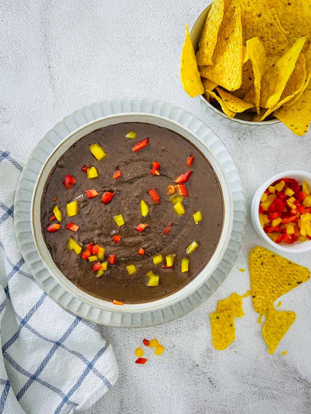 Reried beans topped with red and yellow bell peppers.