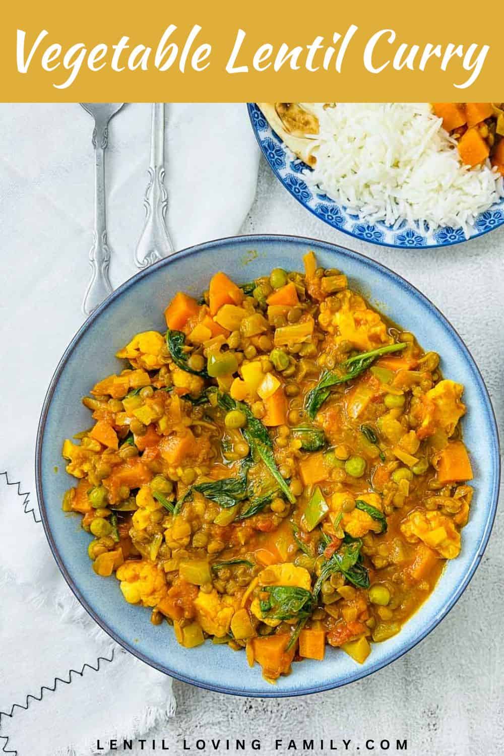 Vegetable lentil curry in a bowl with rice and naan bread in the background.