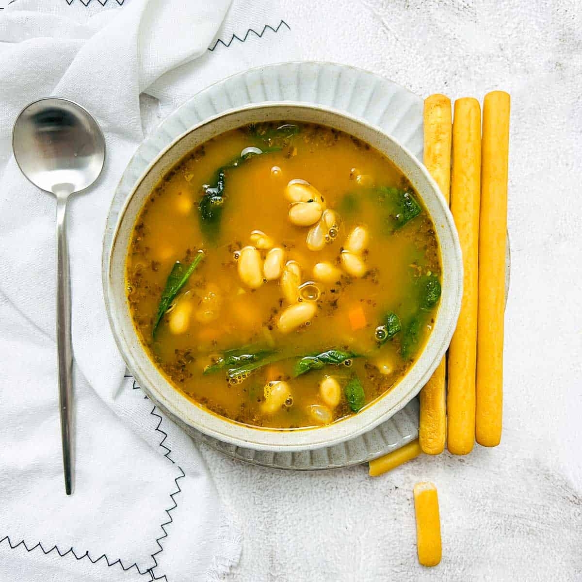 White bean soup in a white bowl.