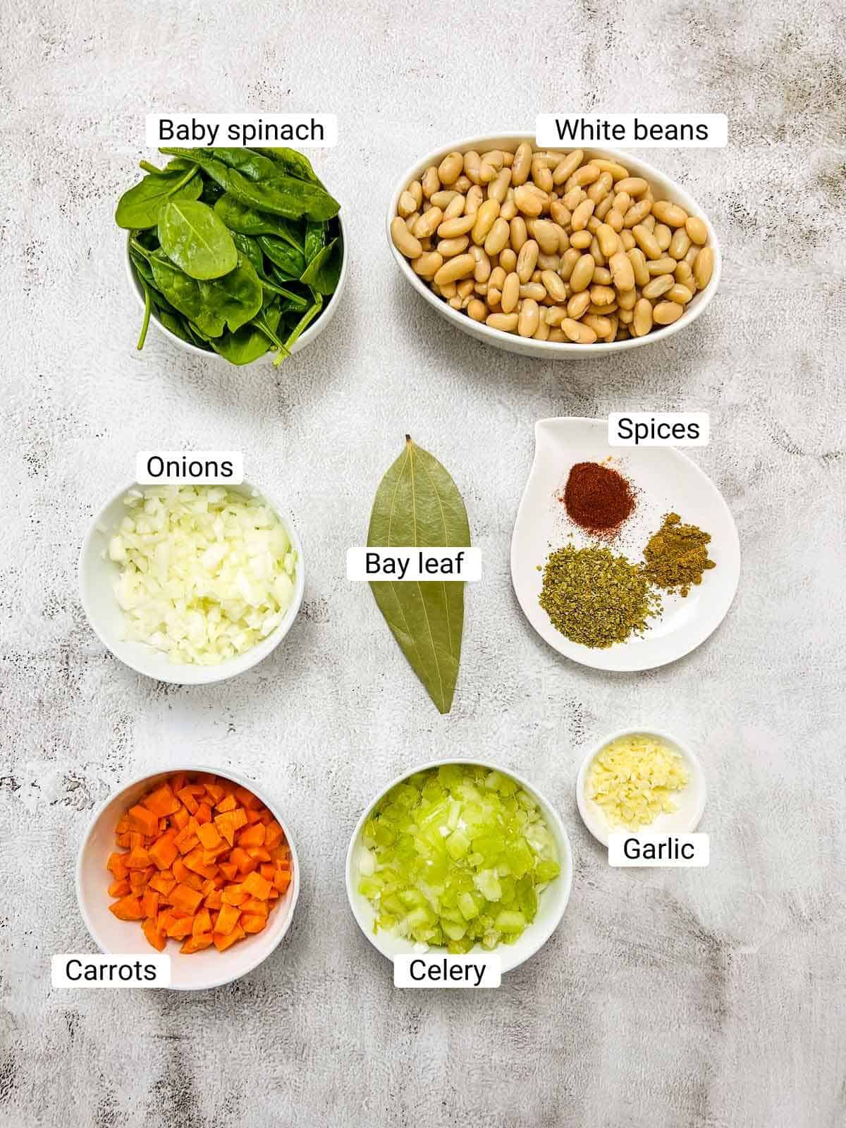 Ingredients to make white bean soup on a white surface.