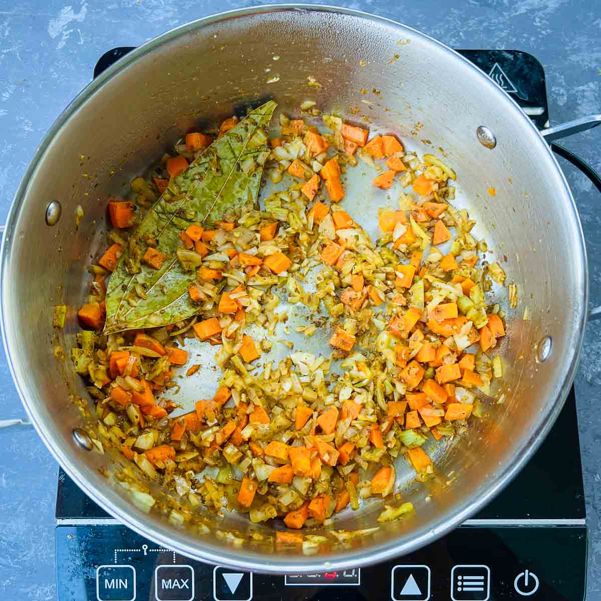 Sauted onion, celery, and carrots in a pot.