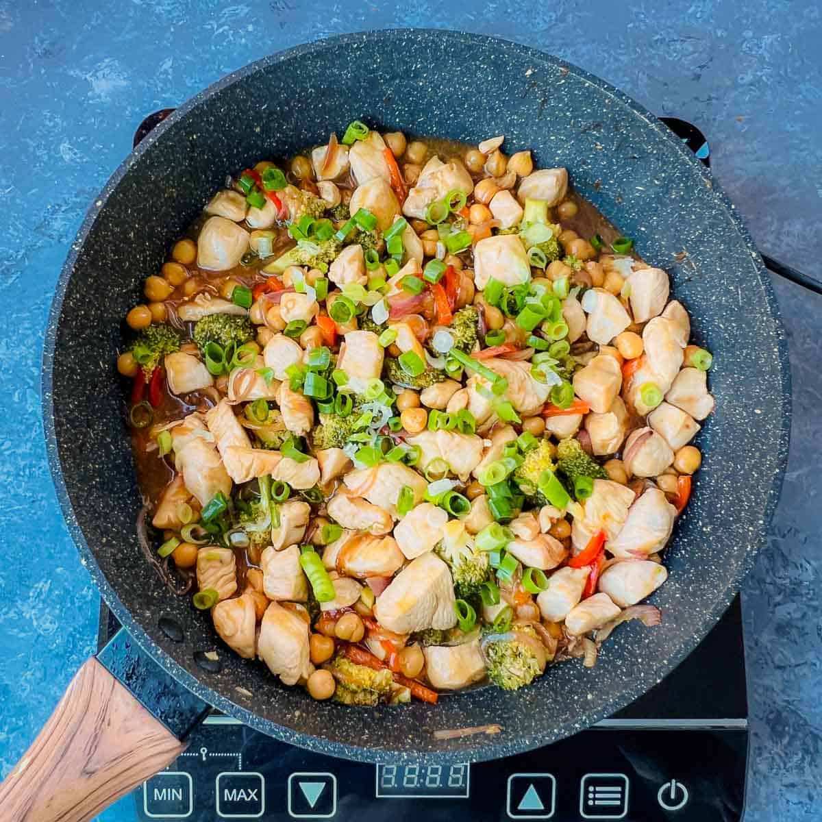 Finished dish garnished with scallions in frying pan.