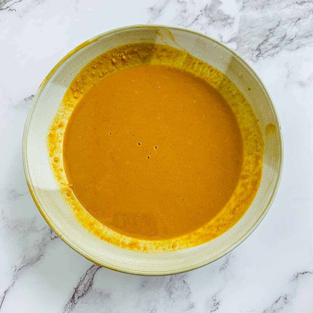 Peanut sauce in a small brown bowl.
