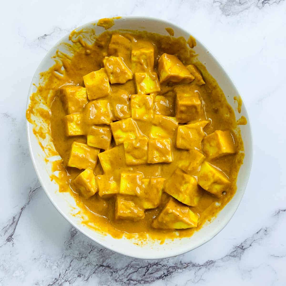 Marinated chickpea tofu in a white bowl.