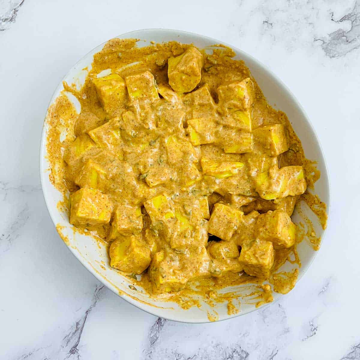 Marinated chickpea tofu in a white bowl.