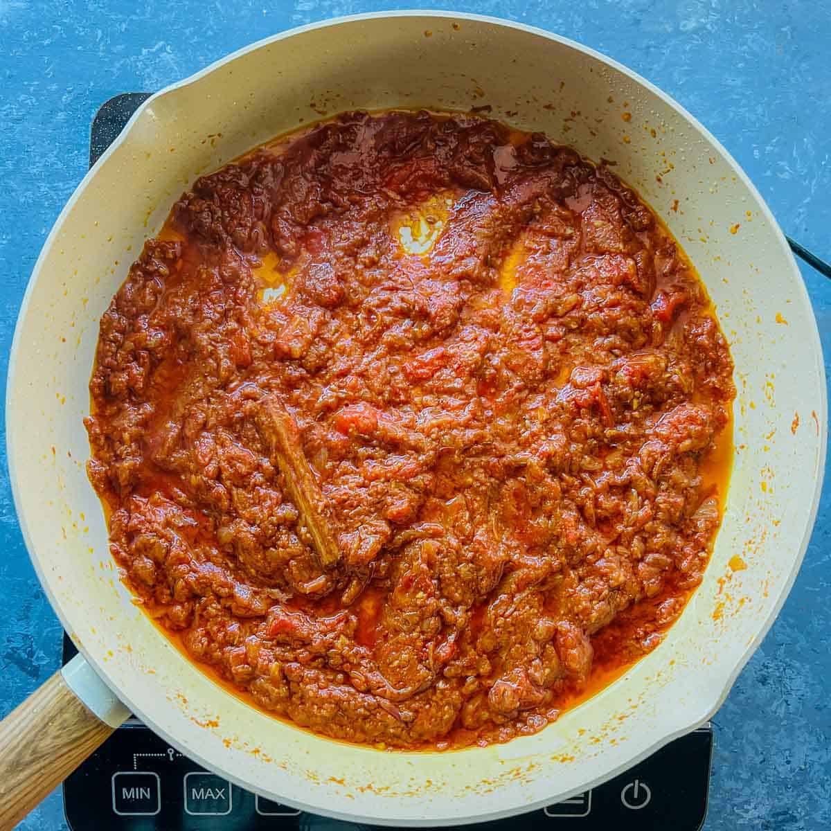 Cooked tomatoes and spices in frying pan.
