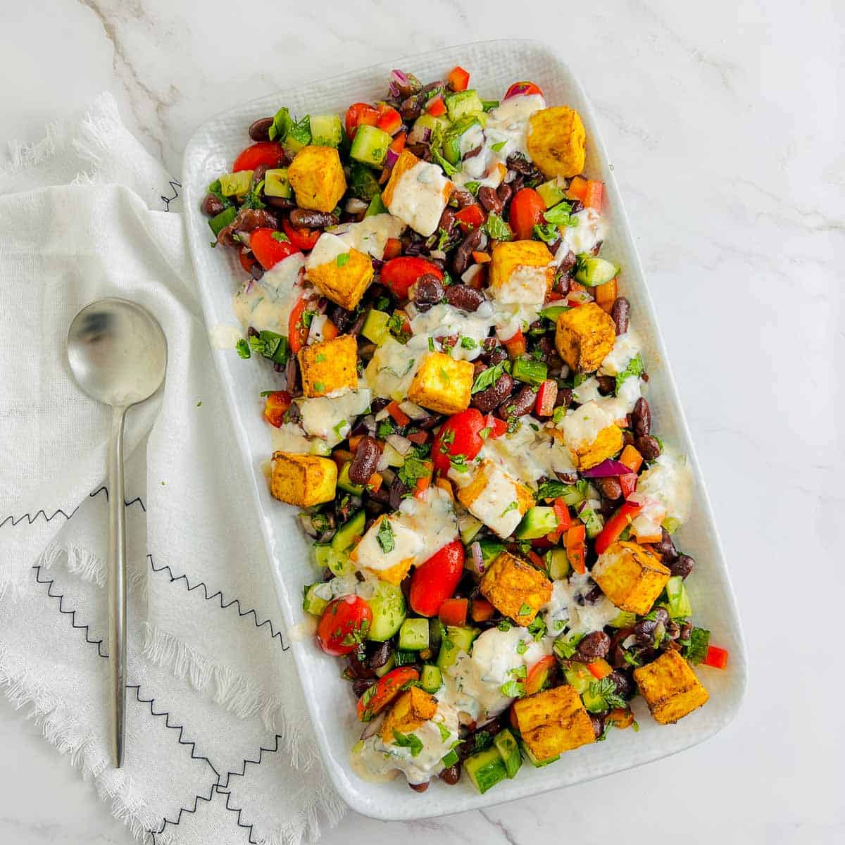 Paneer rajma salad on a white plate with a spoon in the side.
