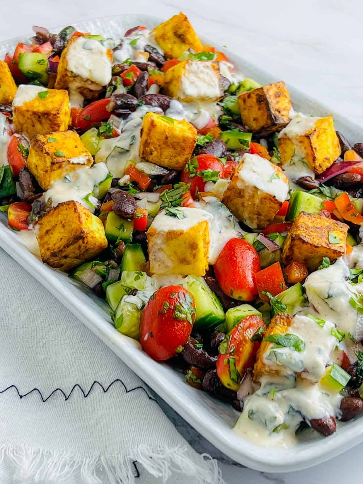 Tandoori paneer and rajma salad with yogurt dressing drizzled on top.