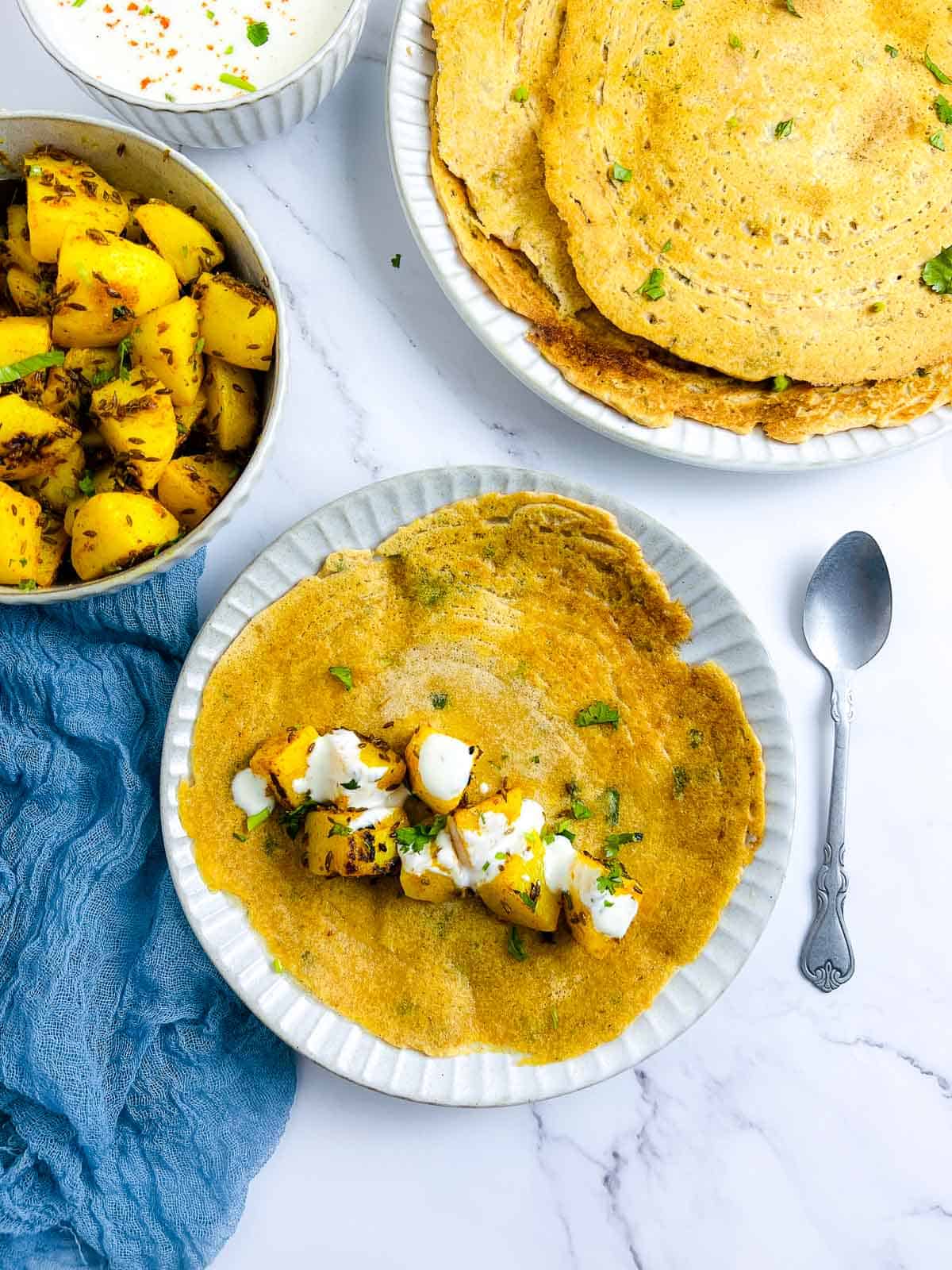 Red lentil pancakes topped with potatoes and yogurt.