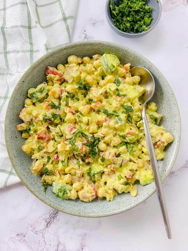 Tuna and chickpea salad in a green bowl with a spoon.