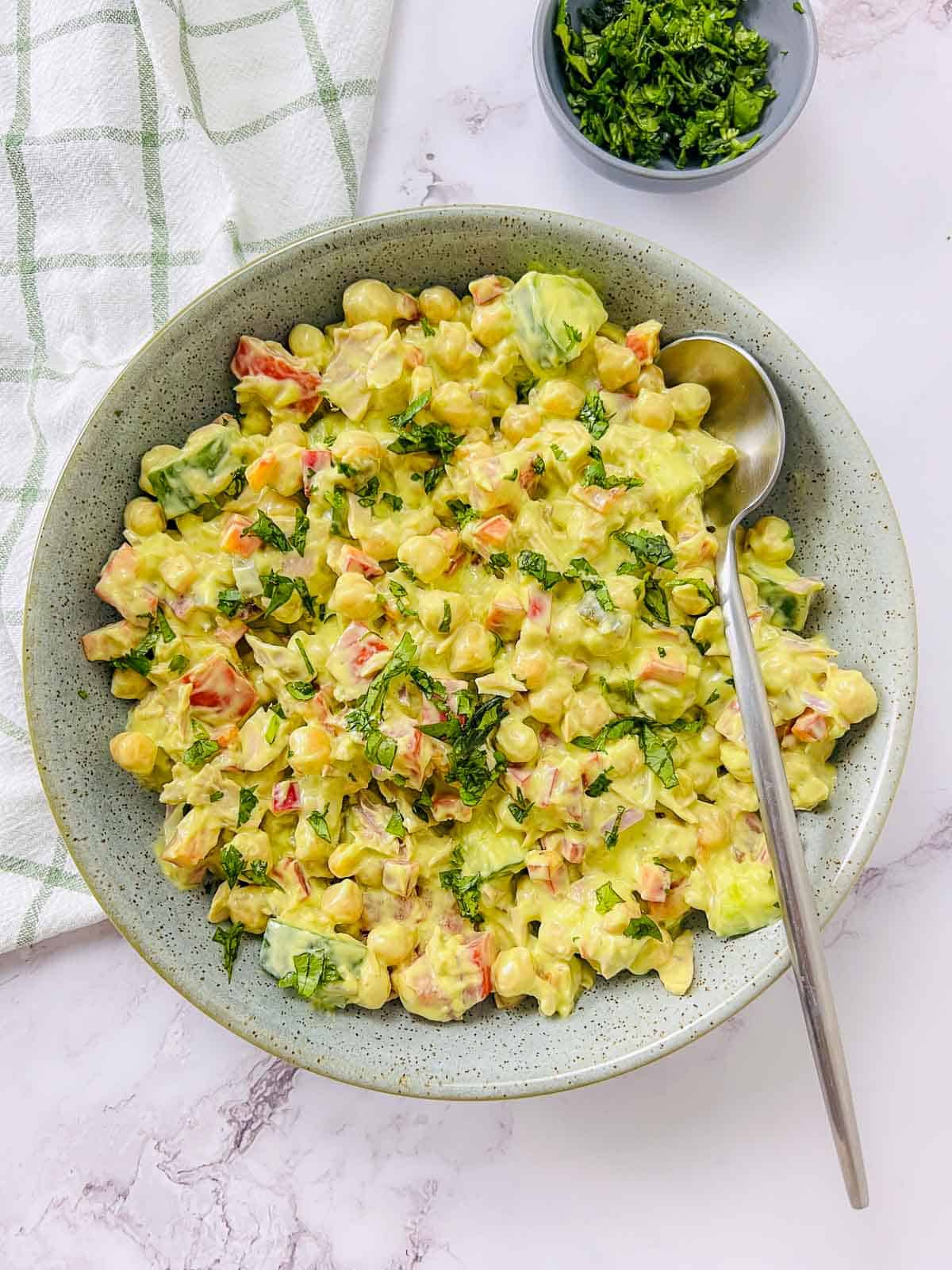 Tuna and chickpea salad in a green bowl with a spoon.
