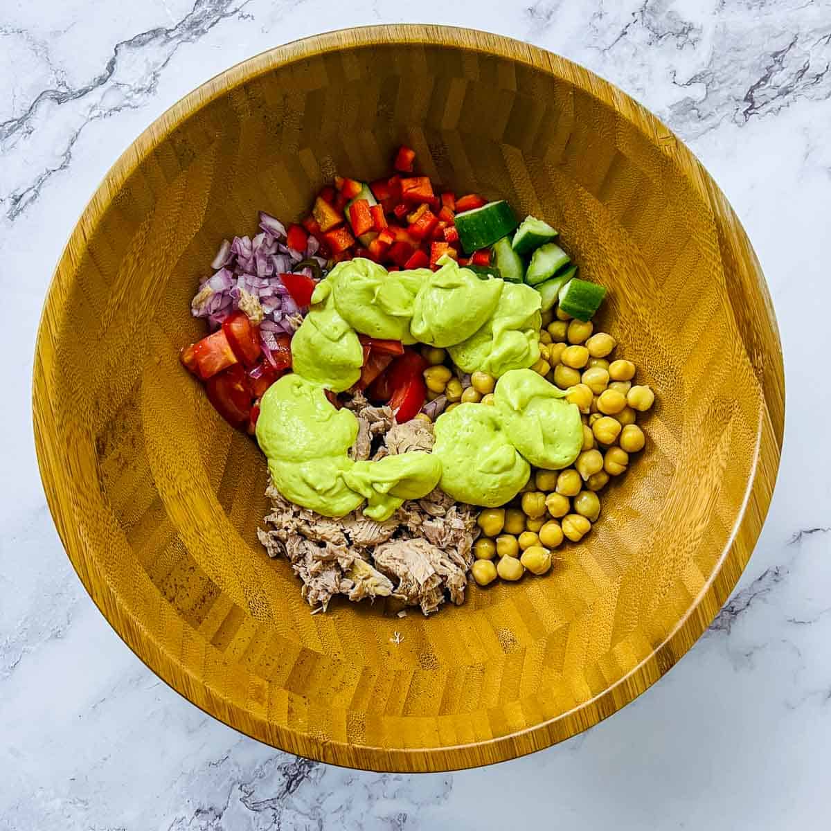 Pouring avocado dressing on the salad ingredients.