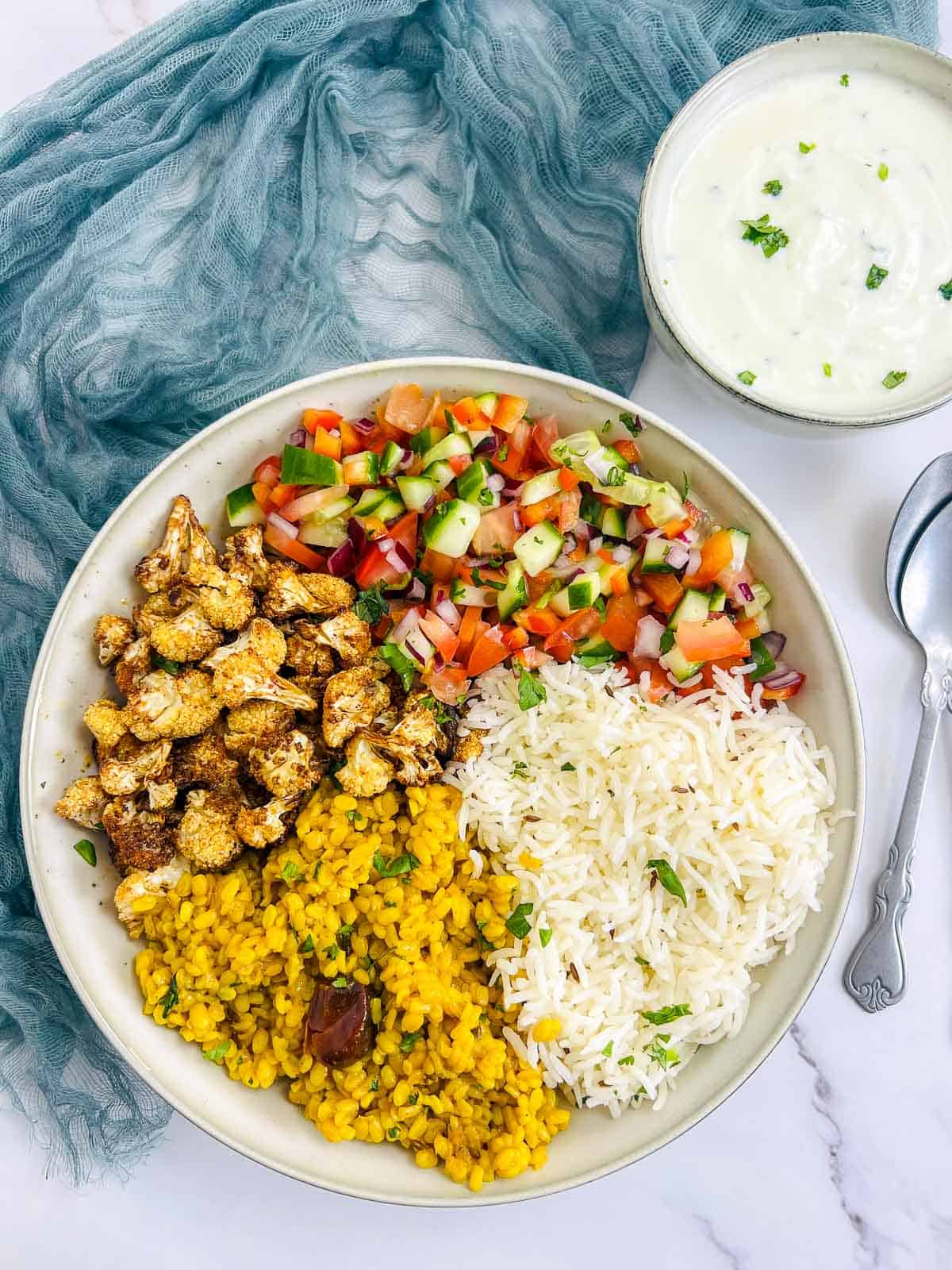Yellow lentils buddha bowl with yogurt raita.