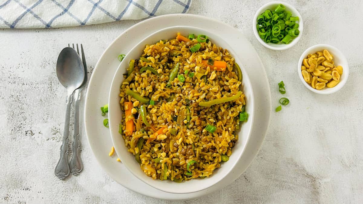Brown rice and lentil stir fry in a white bowl.