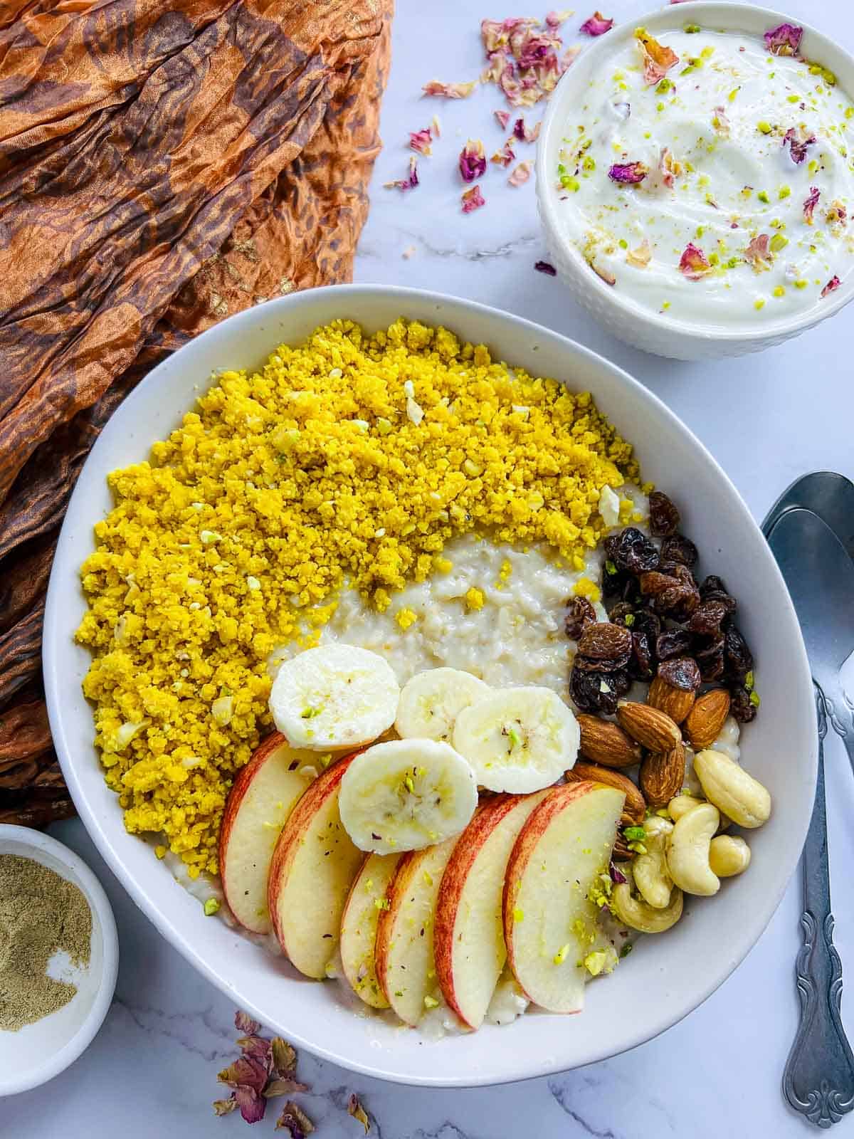 Indian oatmeal breakfast bowl served with rose shrikhand in the background.