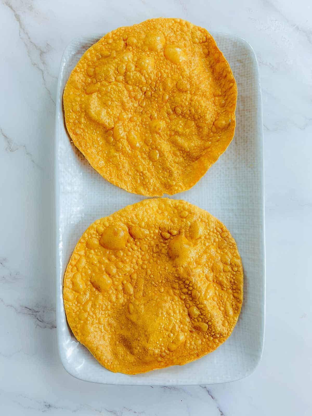 Roasted papadums on a serving plate.