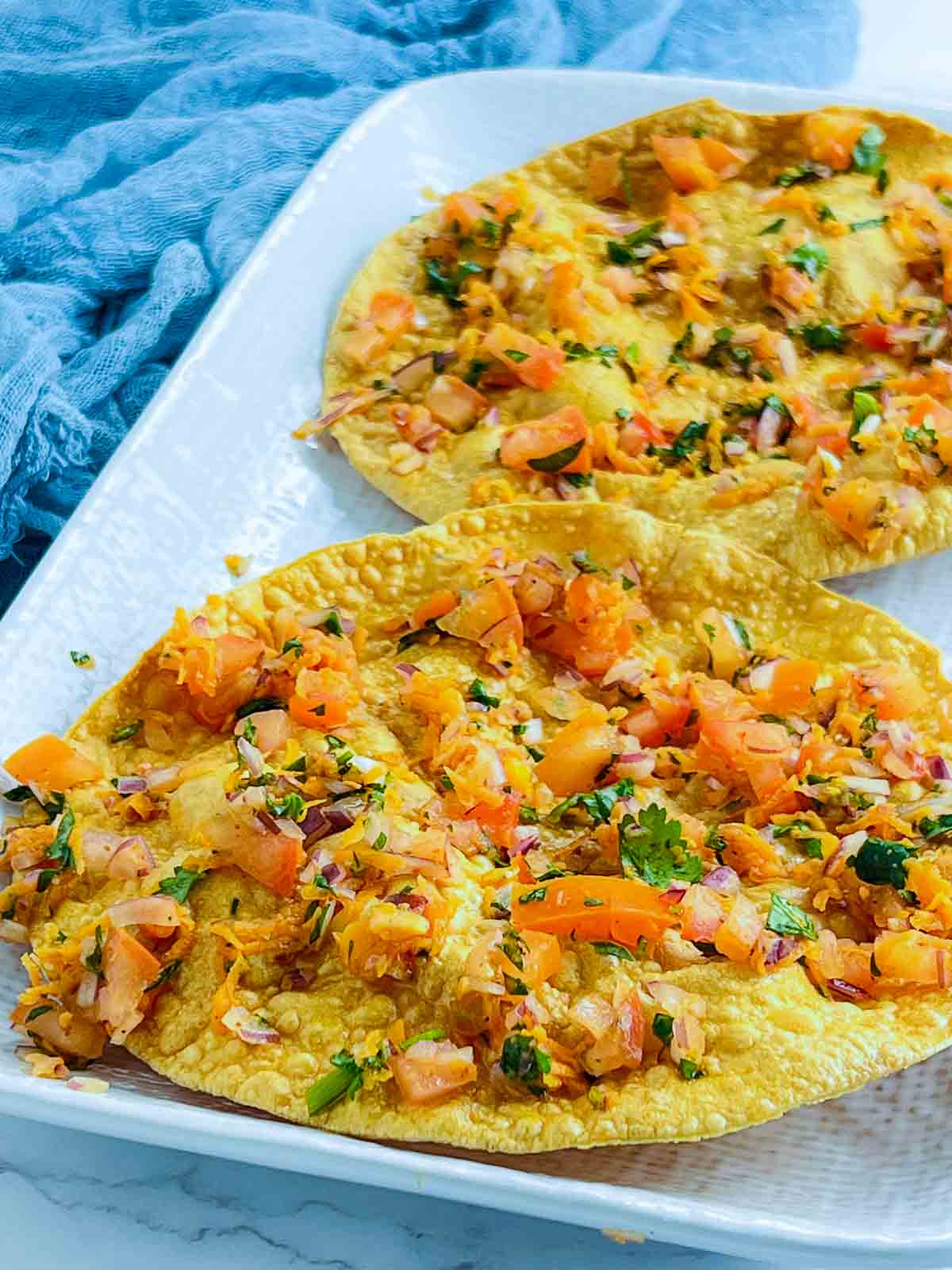 Papad topped with the vegetable and spice mixture.
