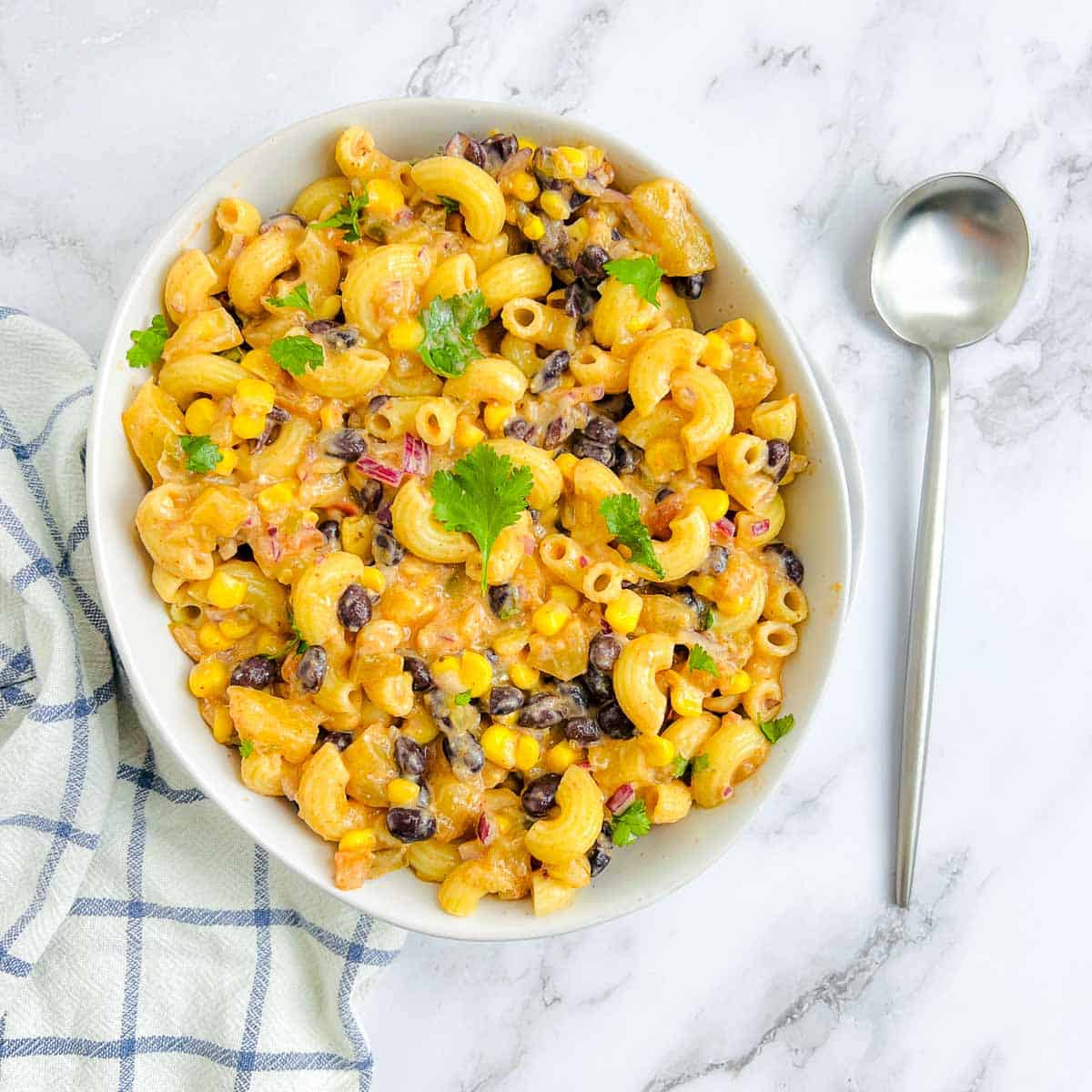 Mexican macaroni salad in a white bowl with a spoon in the background.