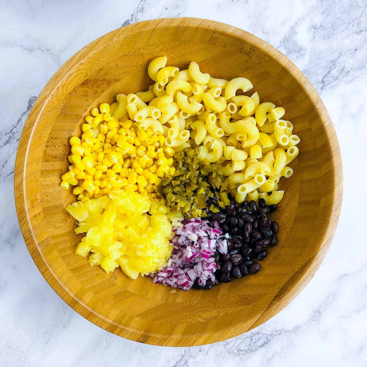 Pasta, beans, and veggies in a mixing bowl.