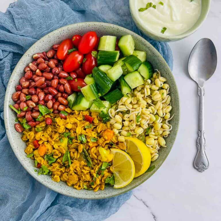 Oats upma breakfast bowl on a white surface with a spoon in the background.