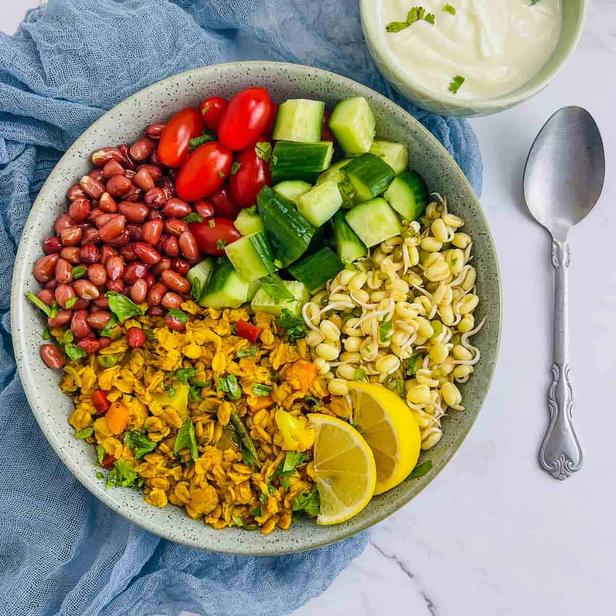 Oats upma breakfast bowl on a white surface with a spoon in the background.