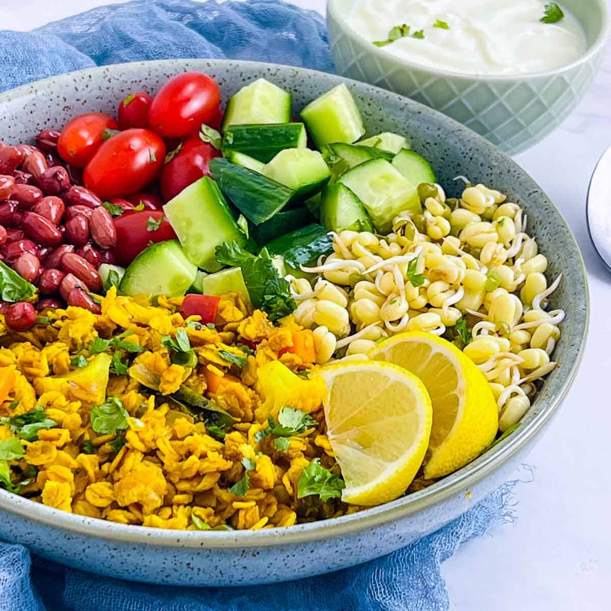 Oats upma breakfast bowl served with yogurt and lemon wedges.