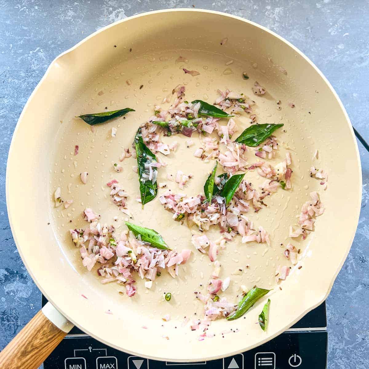 Sauted onion and curry leaves in a pan.