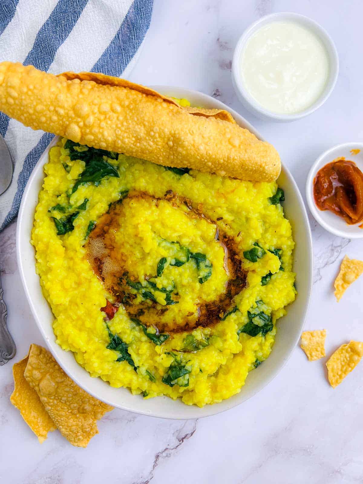 Palak khichdi served with papad, yogurt, and pickle.