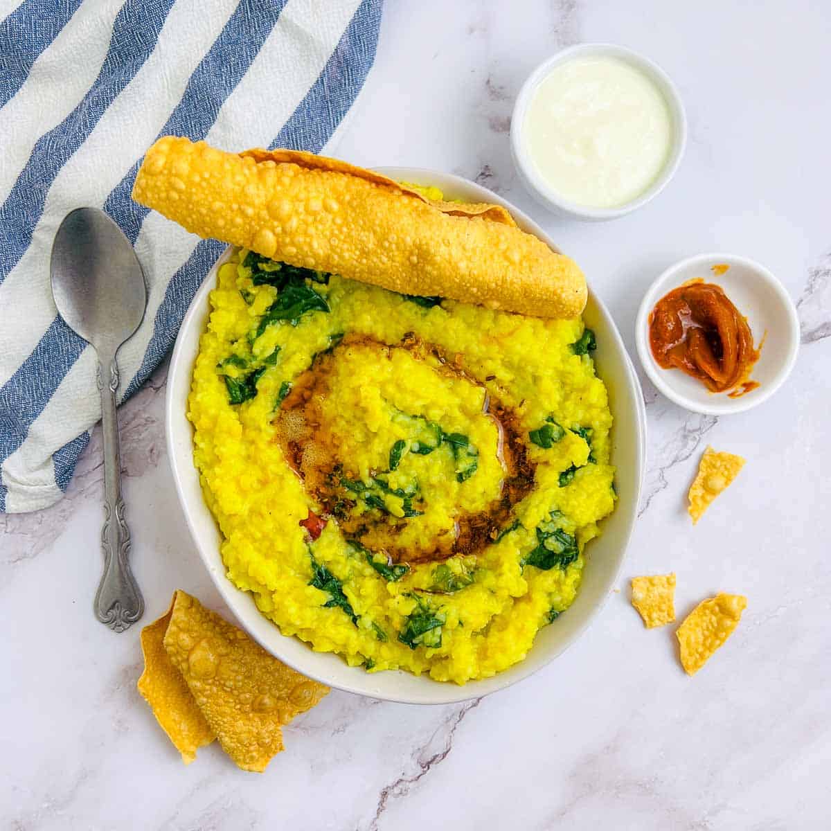 Palak khichdi topped with tempering and papad.