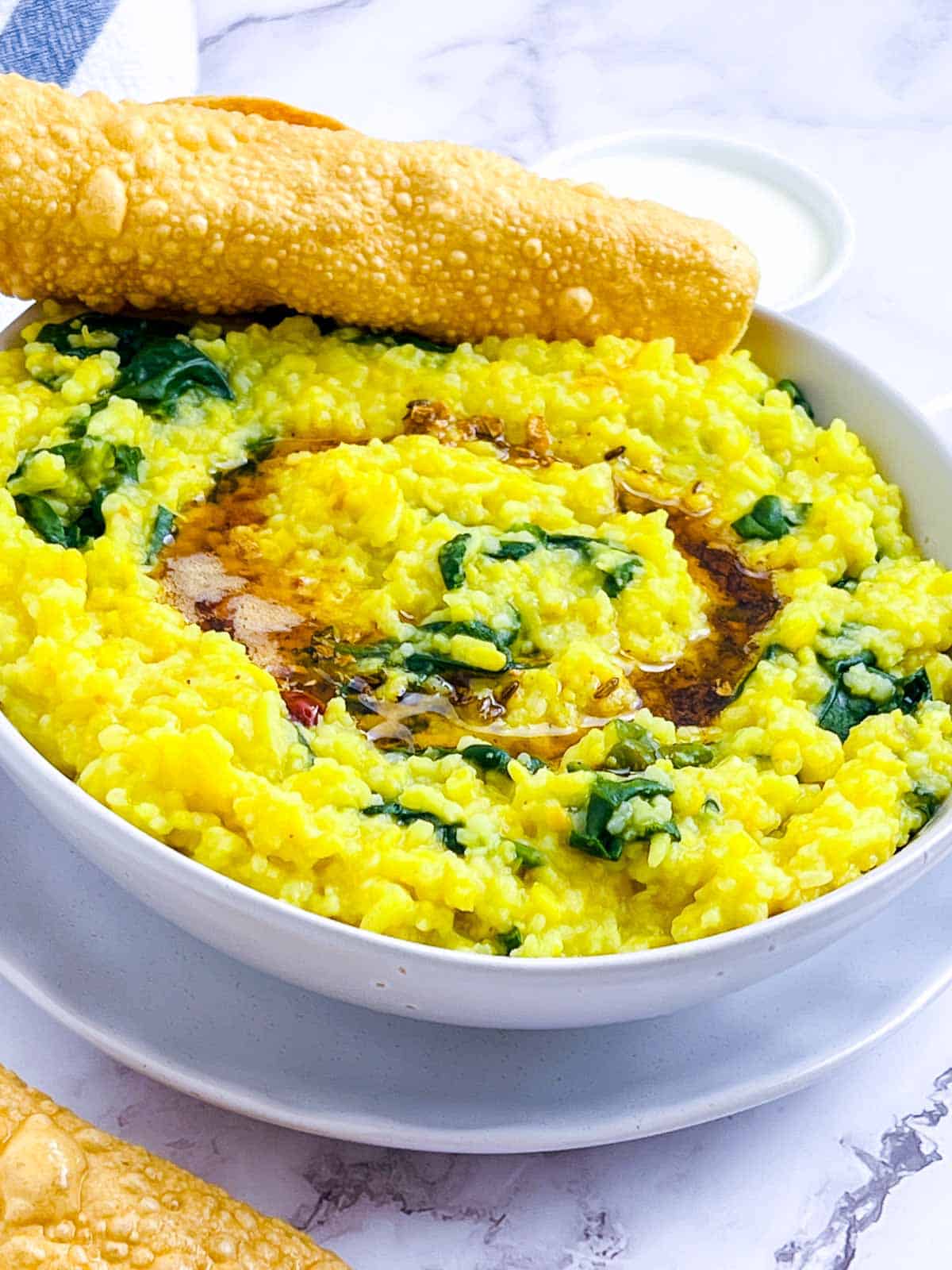 Palak khichdi in a white bowl.