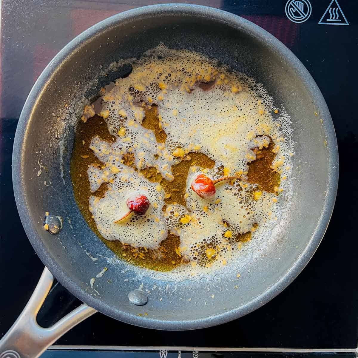 Garlic and spice tempering (tadka) in a small frying pan.