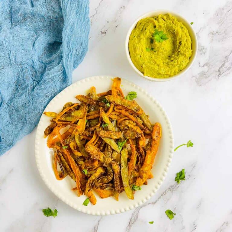 Vegetable peel chips and curried bean dip on a marble surface.