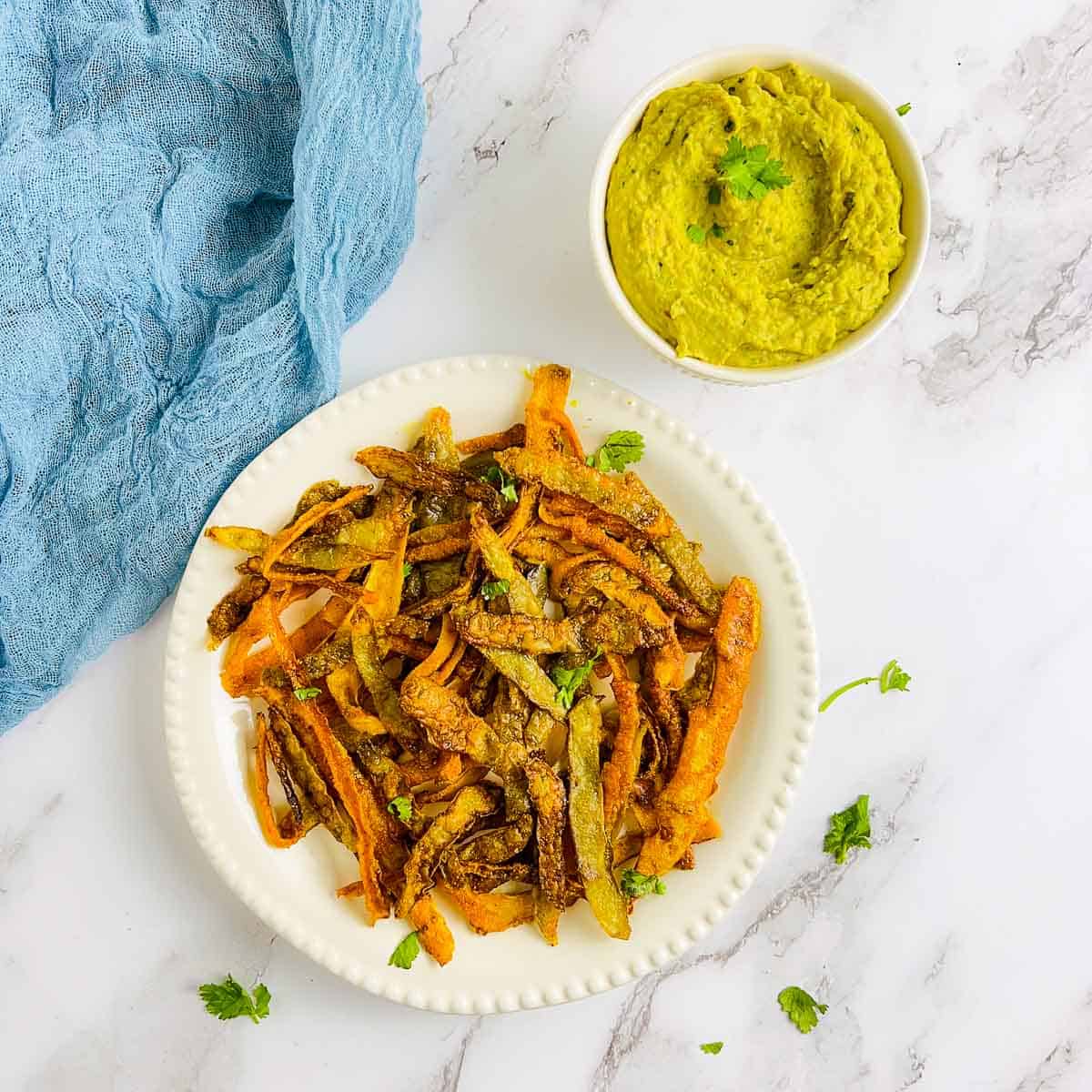Vegetable peel chips and curried bean dip on a marble surface.