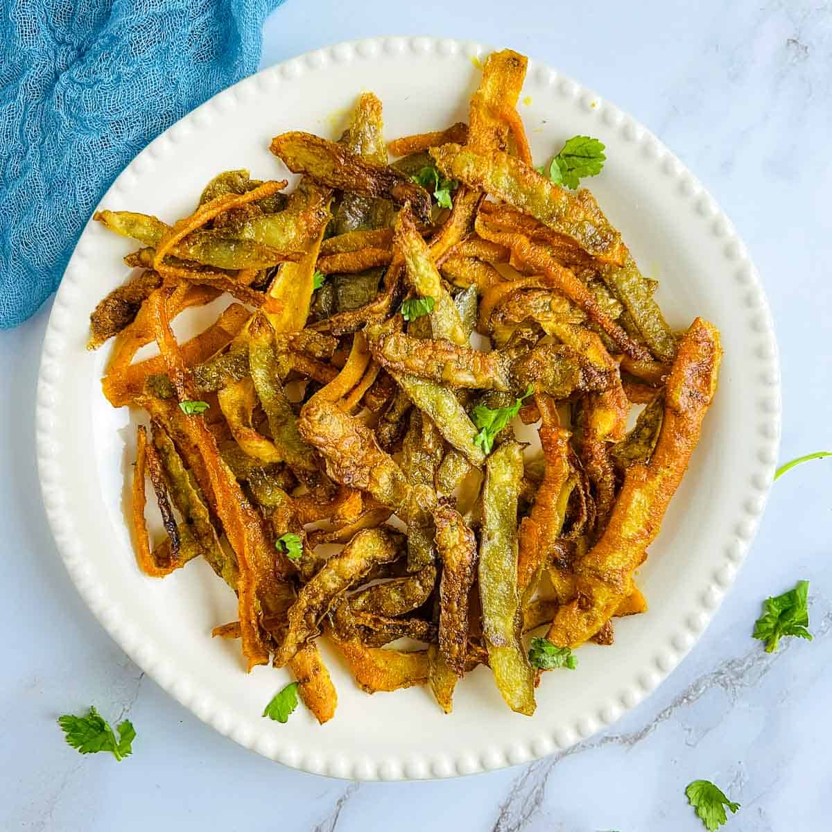 Veggie peel chips served in a white plate.
